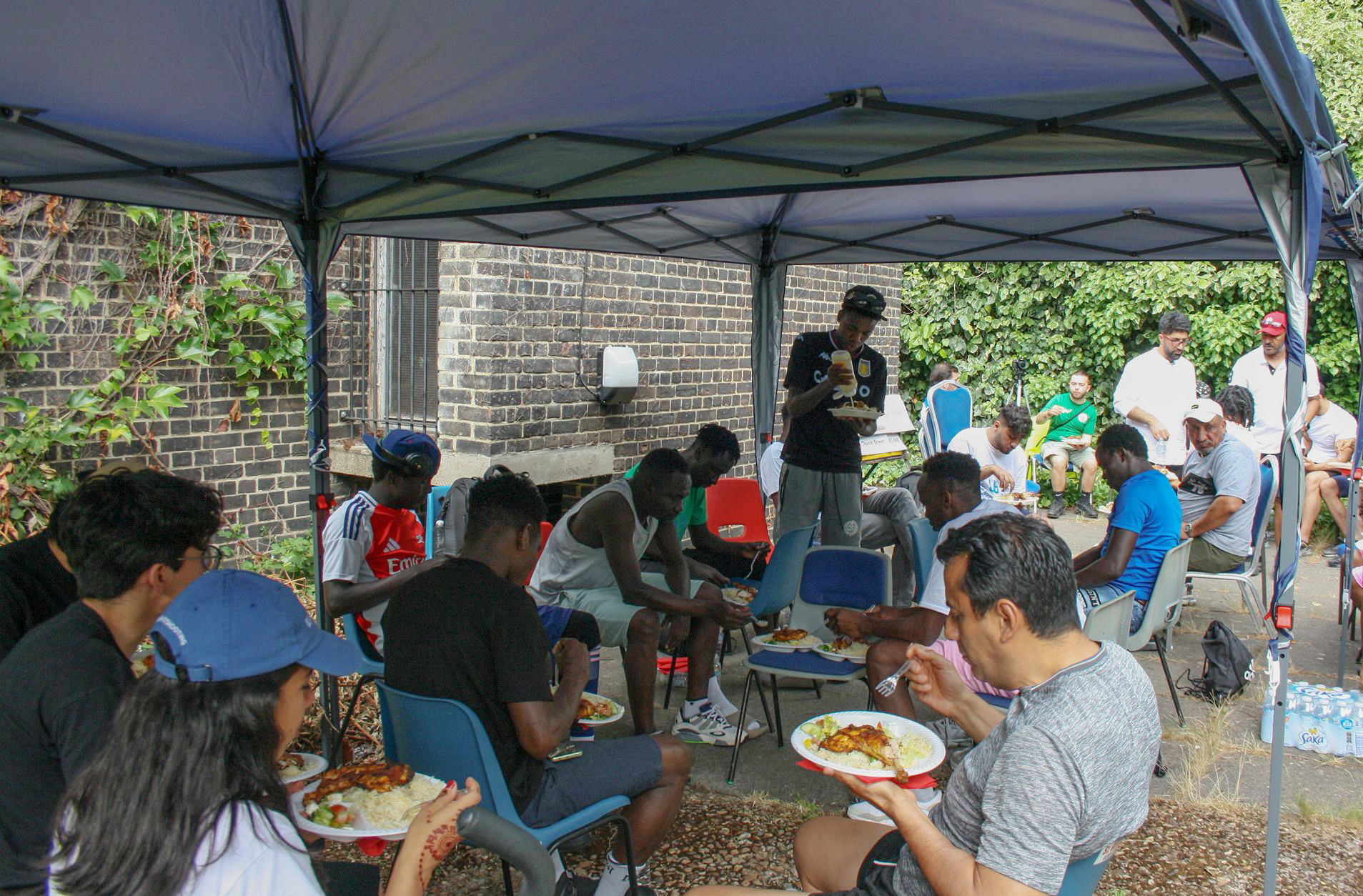 People seated under a marquee enjoying food at a barbecue